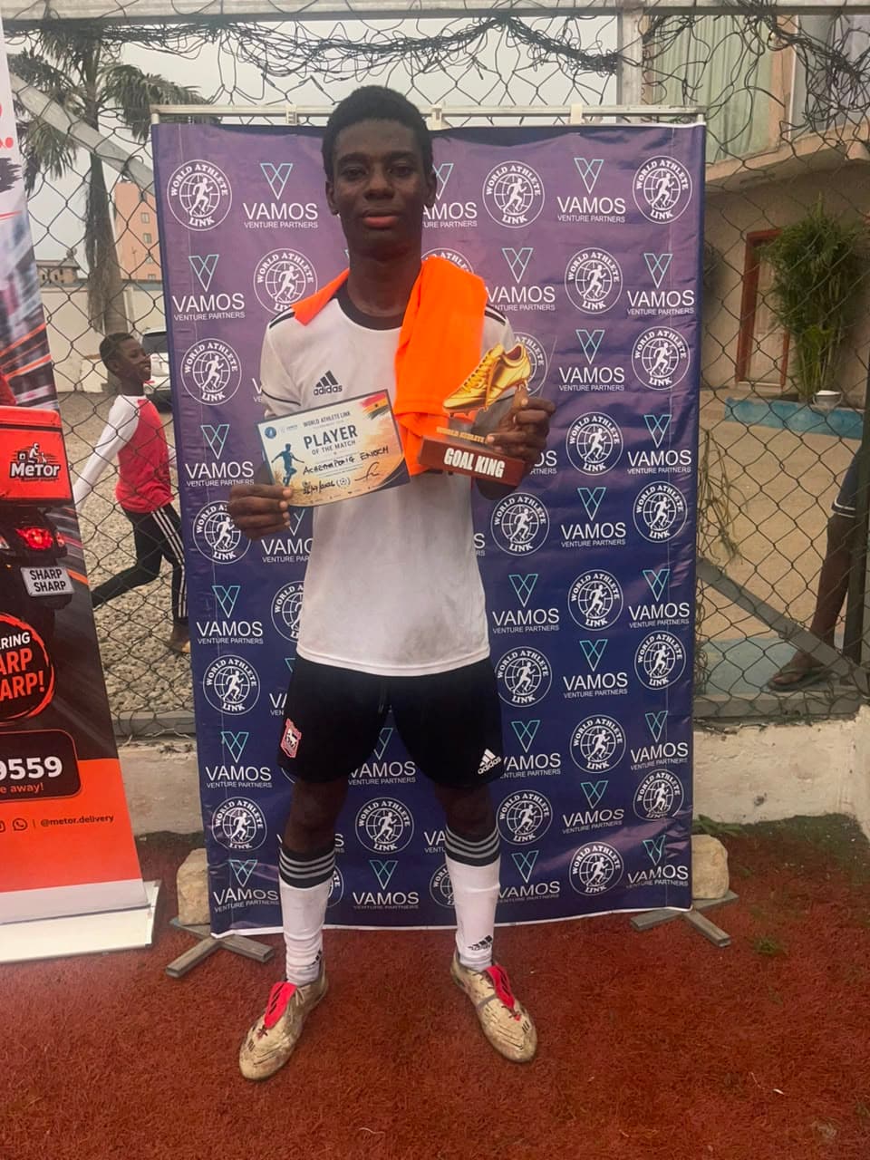 A player holds a certificate and a golden boot Goal King trophy